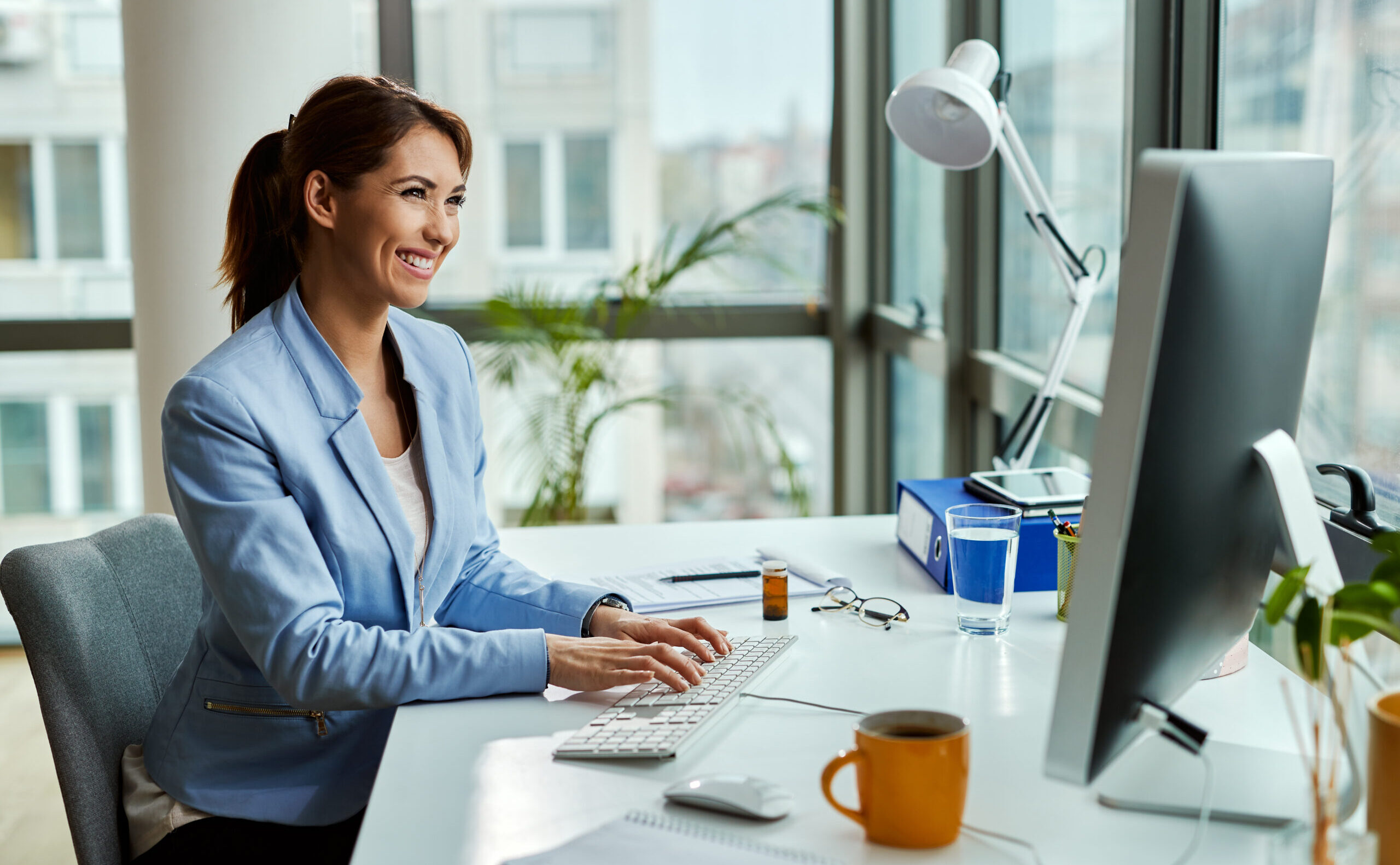Young happy businesswoman using desktop PC while working in the office.
